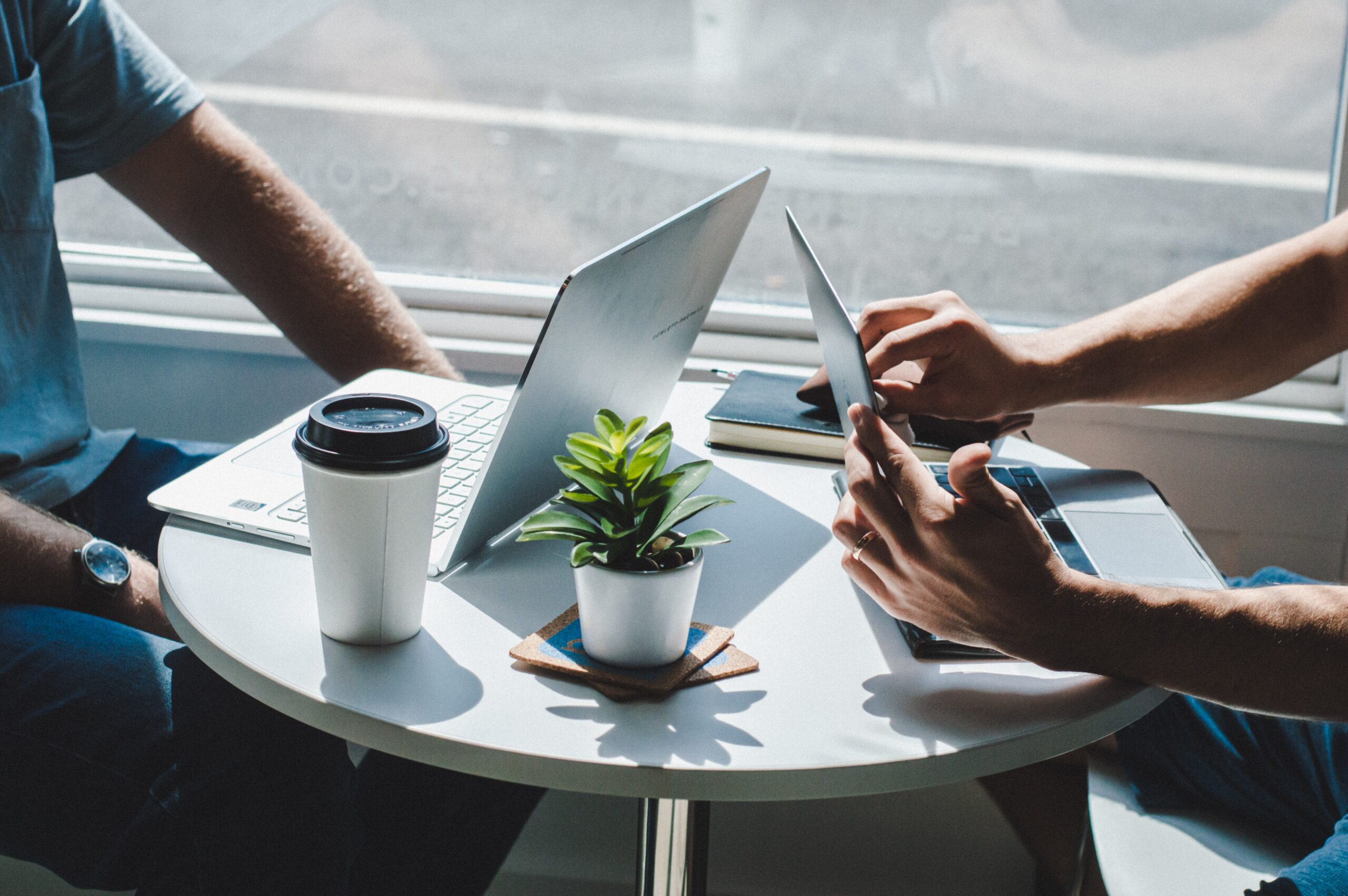 Two persons with laptops in conversation at a table